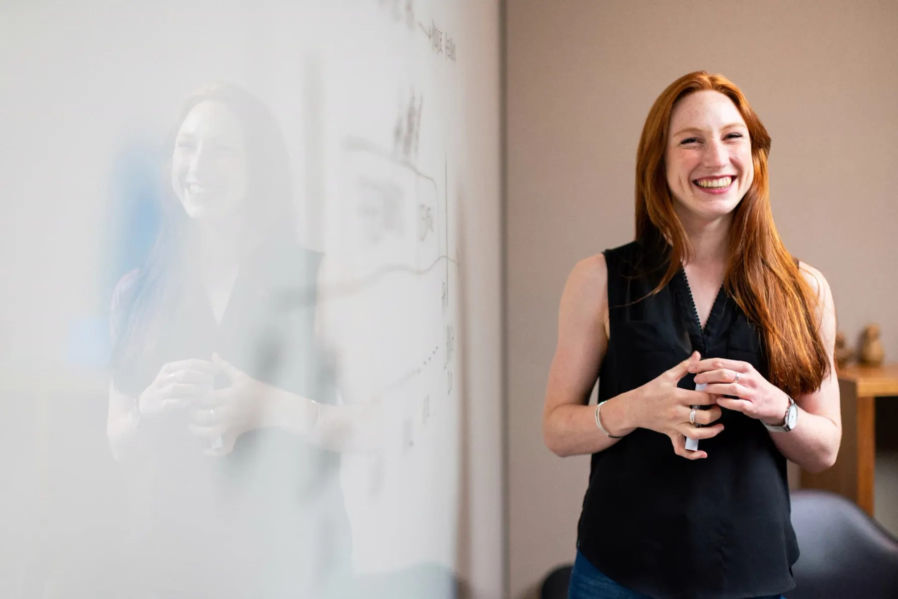 A facilitator laughing beside a whiteboard covered in a hand-drawn plan